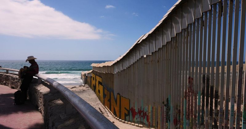 A musician, left, waits to play for visitors along the border walls separating the United States
